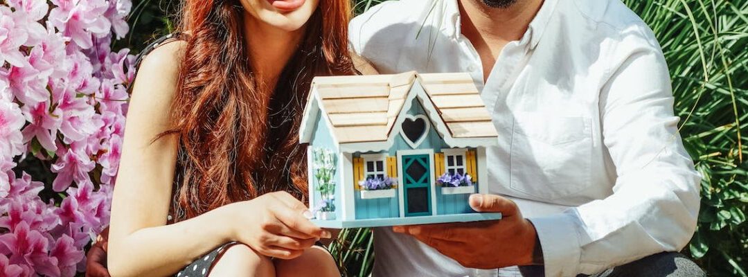 Junges Paar hält das Modell eines Hauses in den Händen